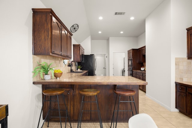 kitchen featuring appliances with stainless steel finishes, a kitchen breakfast bar, backsplash, and kitchen peninsula