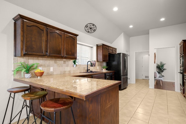 kitchen with a breakfast bar area, sink, kitchen peninsula, backsplash, and light tile patterned floors