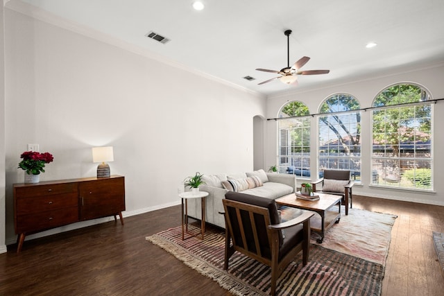 living room with crown molding, ceiling fan, and dark wood-type flooring