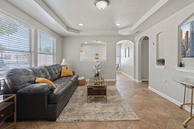 living room with light tile patterned floors and a tray ceiling