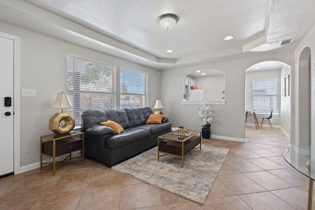 tiled living room with a raised ceiling and a textured ceiling