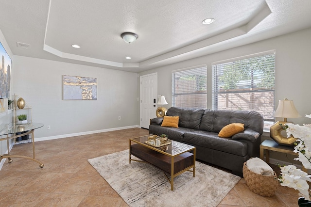 living room with light tile patterned flooring, a raised ceiling, and a textured ceiling