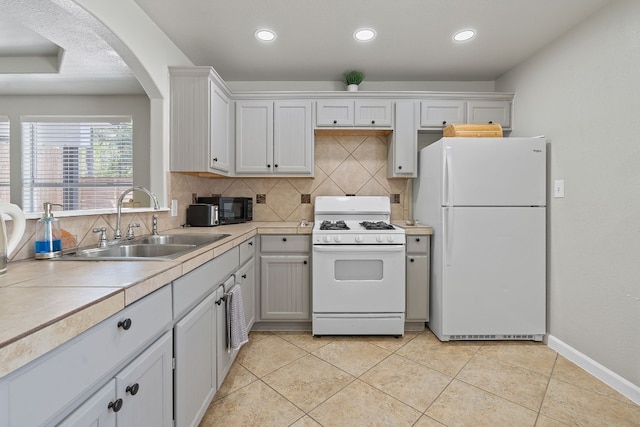 kitchen featuring sink, white appliances, light tile patterned floors, and white cabinets