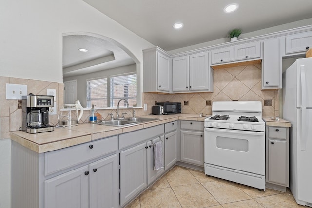 kitchen featuring white cabinetry, sink, decorative backsplash, light tile patterned floors, and white appliances