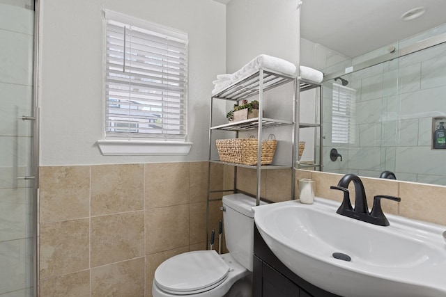 bathroom with vanity, toilet, a shower with shower door, and tile walls