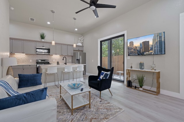 living room featuring ceiling fan, sink, and light hardwood / wood-style flooring