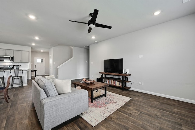 living room featuring ceiling fan and dark wood-type flooring