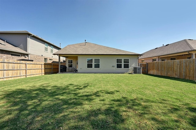 rear view of property featuring a yard and central air condition unit