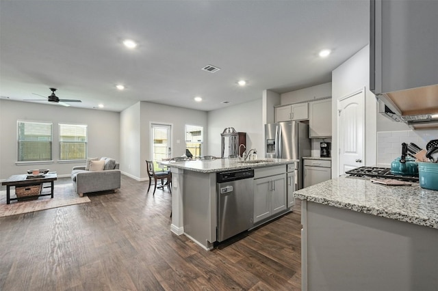 kitchen with light stone countertops, a kitchen island with sink, appliances with stainless steel finishes, and gray cabinets