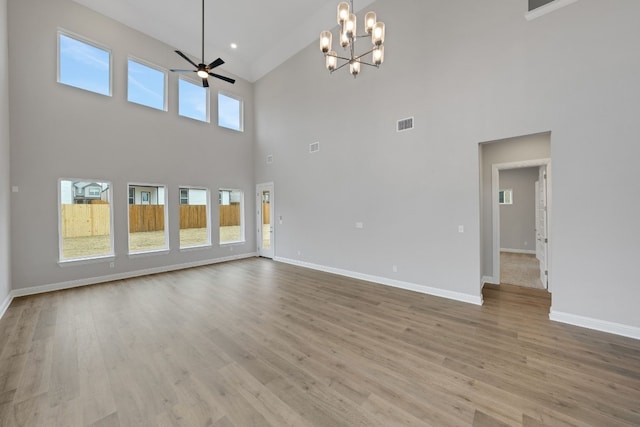 unfurnished living room featuring ceiling fan with notable chandelier and light hardwood / wood-style floors