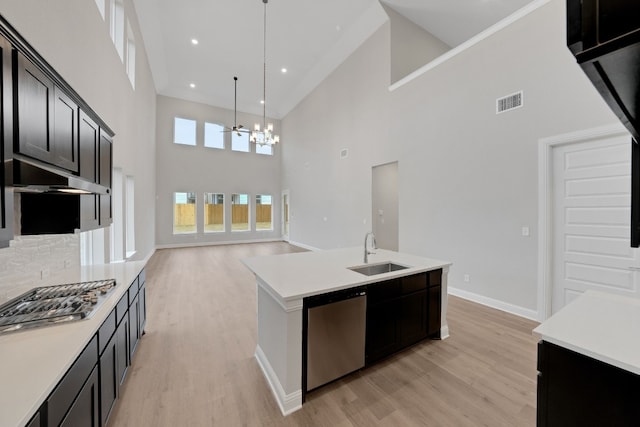 kitchen with an island with sink, sink, hanging light fixtures, light hardwood / wood-style floors, and stainless steel appliances