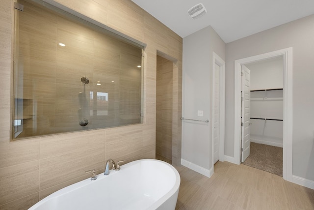 bathroom featuring tile walls and separate shower and tub