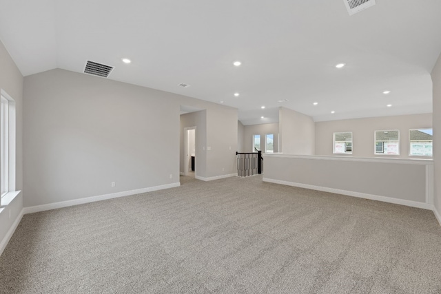 unfurnished room featuring vaulted ceiling, light carpet, and a wealth of natural light