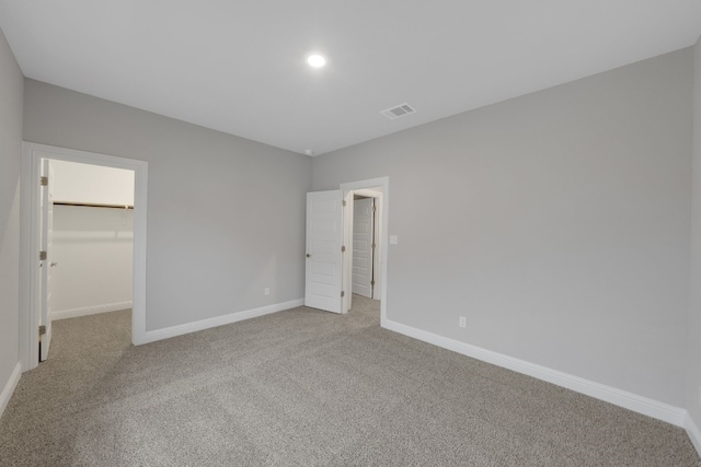 unfurnished bedroom featuring a spacious closet, carpet floors, and a closet