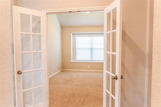 walk in closet with french doors and light colored carpet