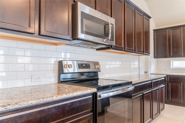 kitchen featuring light stone countertops, stainless steel appliances, decorative backsplash, dark brown cabinets, and light tile patterned floors