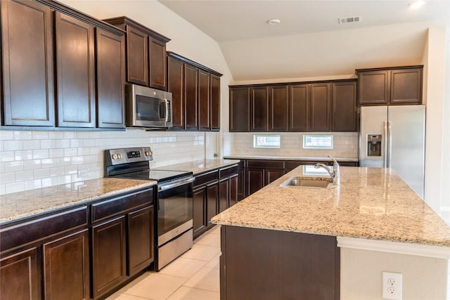 kitchen featuring decorative backsplash, appliances with stainless steel finishes, vaulted ceiling, and a kitchen island with sink