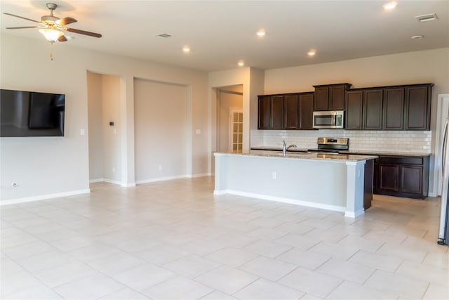 kitchen with ceiling fan, sink, an island with sink, decorative backsplash, and appliances with stainless steel finishes