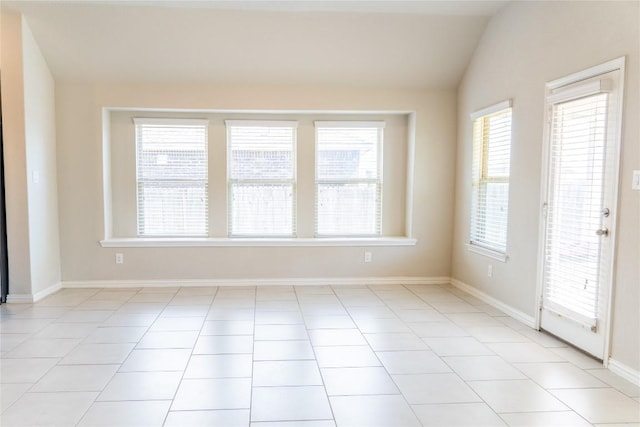 tiled empty room featuring vaulted ceiling and a healthy amount of sunlight