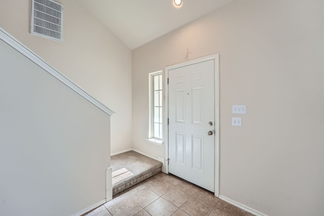 foyer with lofted ceiling and light tile patterned flooring