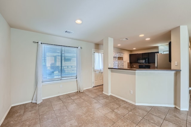 kitchen featuring kitchen peninsula, light tile patterned floors, and stainless steel refrigerator