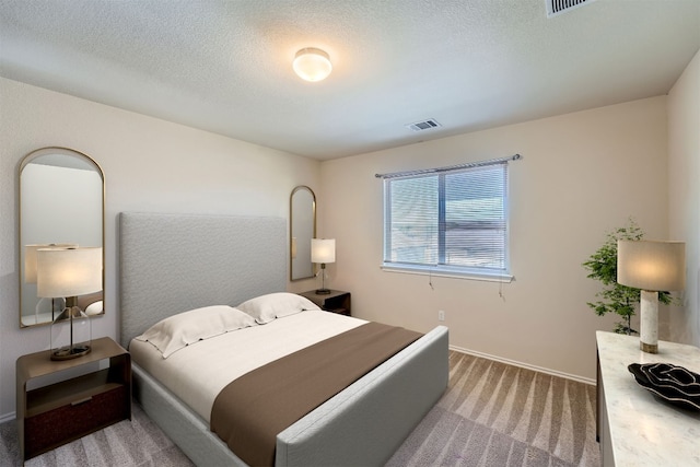 bedroom featuring a textured ceiling and light carpet