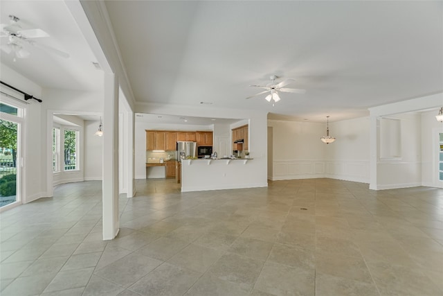 unfurnished living room with ceiling fan, decorative columns, and light tile patterned floors