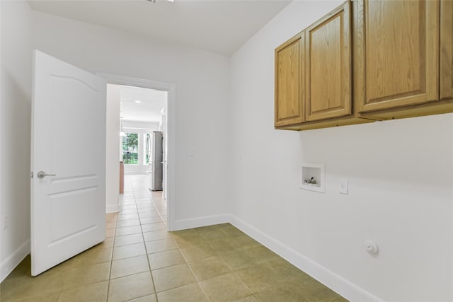 laundry area with hookup for a washing machine, light tile patterned flooring, and cabinets