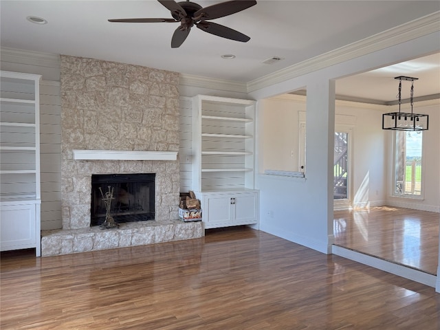 unfurnished living room featuring ceiling fan, a stone fireplace, dark hardwood / wood-style floors, and crown molding