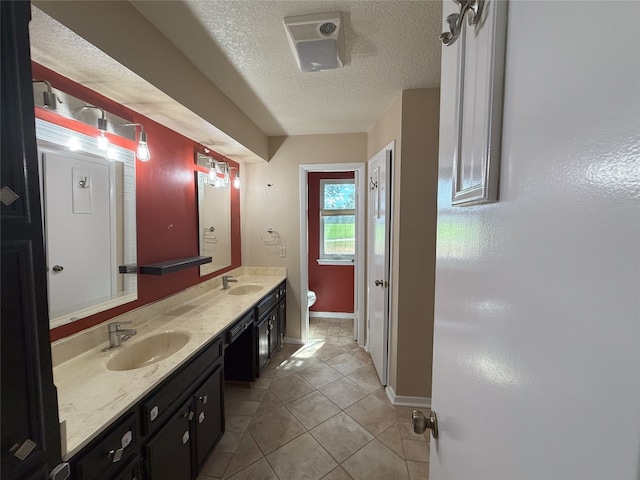 bathroom with vanity, toilet, a textured ceiling, and tile patterned floors