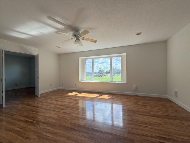 unfurnished room featuring ceiling fan, dark wood-type flooring, and a textured ceiling