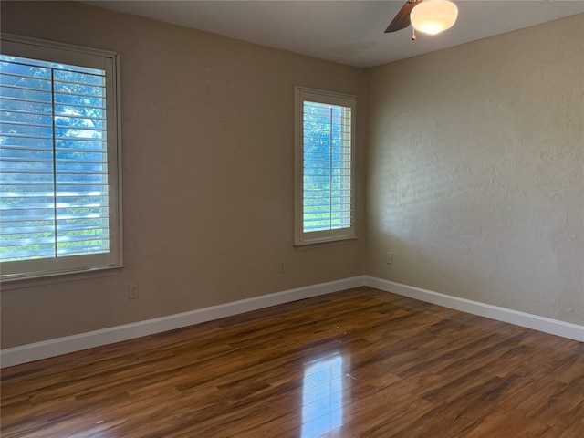 spare room with ceiling fan, plenty of natural light, and dark hardwood / wood-style floors