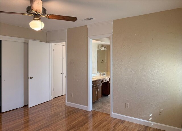 unfurnished bedroom featuring light wood-type flooring, ceiling fan, ensuite bathroom, and a closet