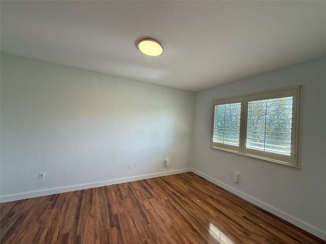 spare room with a textured ceiling and dark hardwood / wood-style flooring