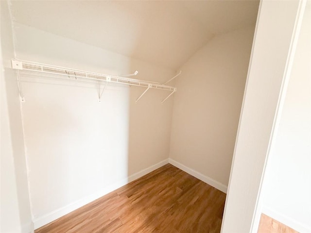 walk in closet with hardwood / wood-style flooring and vaulted ceiling