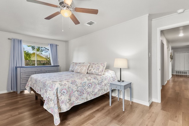 bedroom featuring hardwood / wood-style floors, ceiling fan, and crown molding