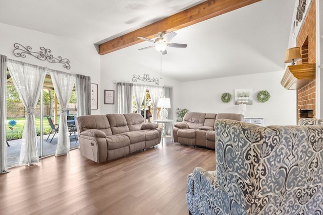 living room with vaulted ceiling with beams, ceiling fan, a fireplace, and dark hardwood / wood-style floors