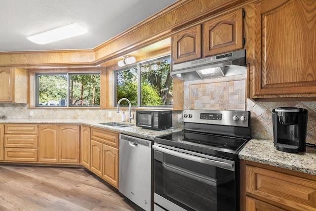 kitchen with light stone countertops, light wood-type flooring, stainless steel appliances, and a healthy amount of sunlight