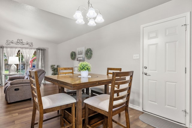 dining space with a chandelier, dark wood-type flooring, and vaulted ceiling