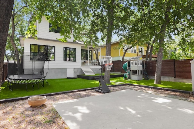 back of property featuring a patio, a playground, a trampoline, and a lawn