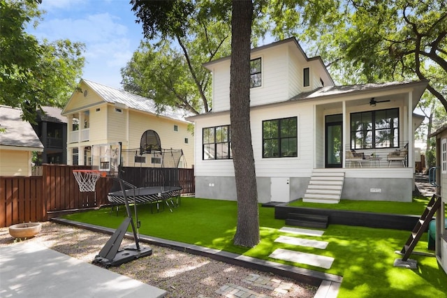 rear view of house featuring a yard and a trampoline