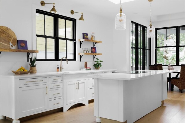 kitchen featuring hanging light fixtures, white cabinetry, a center island, and light hardwood / wood-style flooring