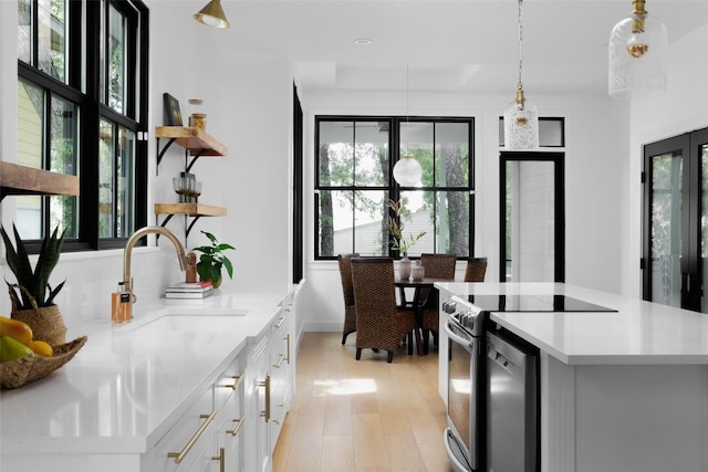 kitchen featuring decorative light fixtures, white cabinetry, sink, stainless steel range with electric stovetop, and a healthy amount of sunlight