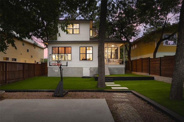 back house at dusk featuring a sunroom and a yard