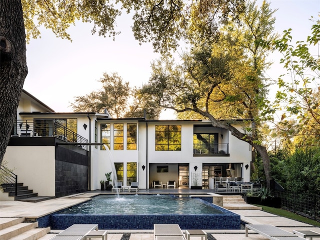 back of house featuring pool water feature and a balcony