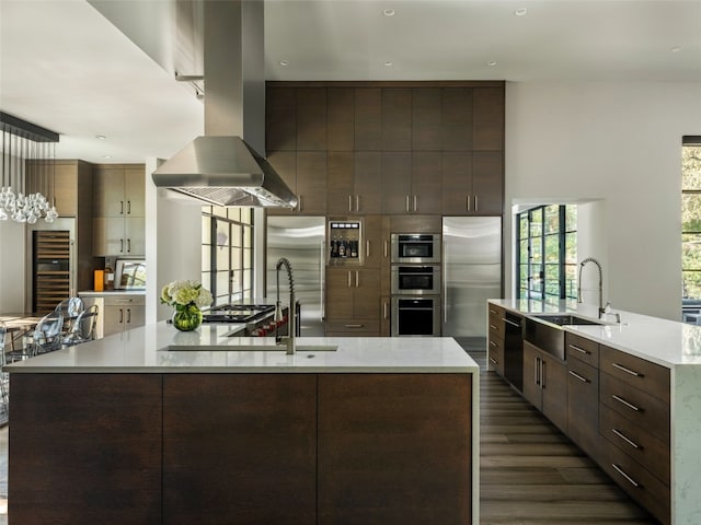 kitchen featuring dark wood-type flooring, a spacious island, sink, island range hood, and stainless steel appliances