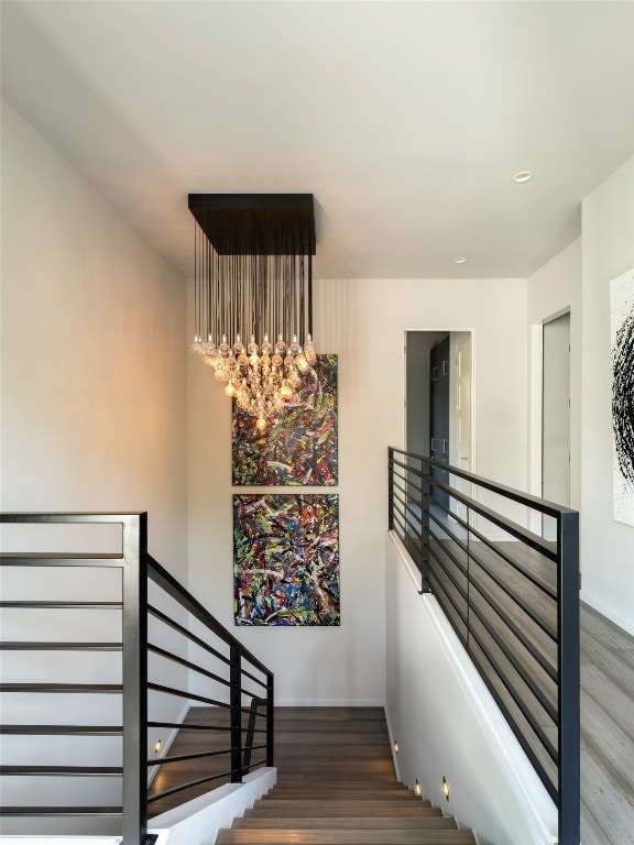 staircase with a chandelier and hardwood / wood-style flooring