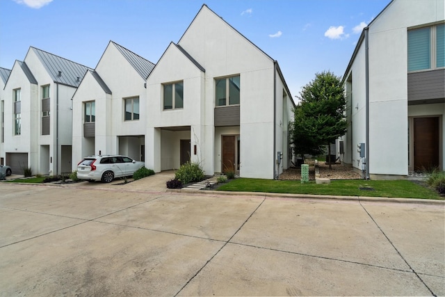 view of front facade with a standing seam roof, a residential view, metal roof, and stucco siding