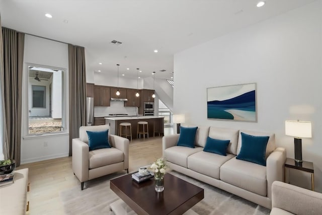 living room featuring light wood finished floors, visible vents, and recessed lighting