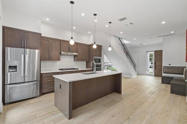 kitchen with sink, hanging light fixtures, an island with sink, dark brown cabinets, and stainless steel appliances